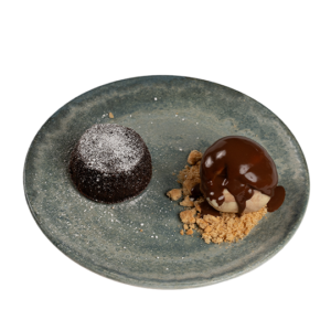 Warm chocolate fondant dusted with powdered sugar, served alongside vanilla ice cream and chocolate sauce.