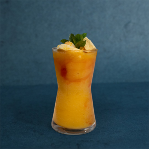 Fresh mango juice served in a tall glass, garnished with mint leaves and mango pieces.