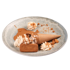 Broken waffle cone filled with Lotus Biscoff ice cream, topped with whipped cream and Lotus spread, served with a Biscoff biscuit on a ceramic plate.