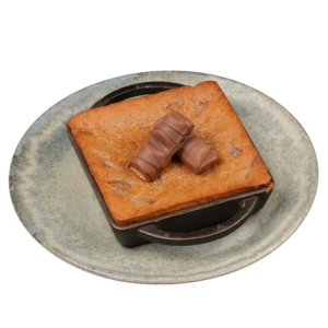 Warm square Kinder Bueno cookie lava cake served in a small skillet, topped with Kinder Bueno chocolate pieces on a ceramic plate.